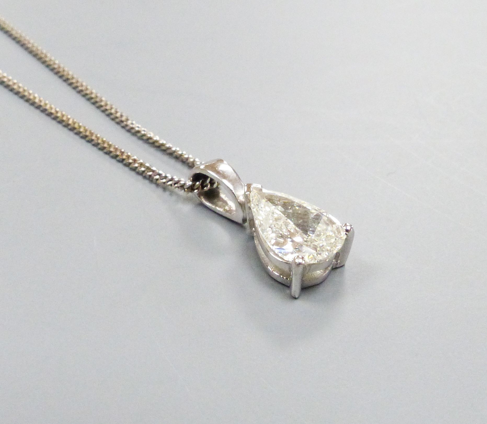 A modern white metal and solitaire pear shaped diamond set pendant, overall 14mm, on and 18ct white gold fine link chain, 40cm, gross weight 2.9 grams